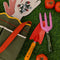 army green canvas gardening tool bag with red strap and yellow scalloped top edge surrounded by gardening items