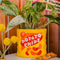 yellow potato chips shaped vase with flowers inside surrounded by various 'camp' items