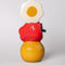 back view of stacked vase with white flower, an apple on it's side and smiley face