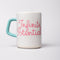 ceramic mug with paper lines and pink cursive 'infinite potenial' typography across the front and light blue handle