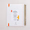 back view of white lined paper large 12-month planner with cursive 'ready for anything' font and orange elastic closure