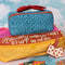 blue quilted zipper makeup bag with red bow handle and all blue floral and bow print on a colorful packing cube