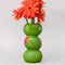 three green olives stacked vase with gerber daisies inside