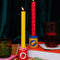 set of a peanut butter jar and jelly jar candle holders with colorful taper candles inside and surrounded by colorful kitchen items
