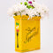 side view of yellow pasta box ceramic vase that says 'BUON APPETITO' with flowers inside