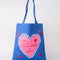 blue tote bag with pink heart and 'THE SMELL OF PASTRIES AND BOOKS' across the front