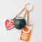 fidget keychain with gold heart photo frame, enamel orange juice charm, and 8-ball de-stress ball