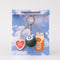 packaged fidget keychain with gold heart photo frame, enamel orange juice charm, and 8-ball de-stress ball