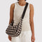 model wearing medium nylon crescent bag with brown blurred gingham print