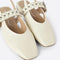 up close of front of cream slingback flat with large grommet buckle and square toe