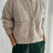 model wearing cream/tan oversized cardigan with shell buttons and two front patch pockets
