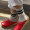 model wearing heather grey crew socks with double black stripes at the top and red shoes