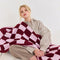 model holding light pink and burgundy checkered blanket