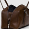 side view of medium brown recycled dome bowler bag with silver charm clasp