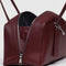 side view of medium mahogany recycled dome bowler bag with silver charm clasp