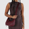 model wearing mahogany recycled leather small crescent bag with silver charm clasp