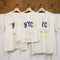 three hanging white upcycled tees with navy NYC across the front