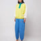 model wearing relaxed fit color block sweatshirt with yellow body, white sleeves, teal zipper placket and navy collar