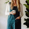 model wearing peacock blue cotton apron with large front pocket and criss-cross back
