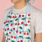 up close of model wearing blue gingham cherry print cotton apron with blue grid patch pockets and straps