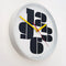 side view of white round wall clock with large black numbers with yellow and red hands