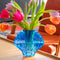 cobalt blue glass seashell vase with tulips inside on a table