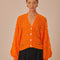 model wearing orange open knit textured cardigan with slight puff sleeves and fashion button front