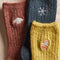 up close of speckled crew socks: navy socks with snowflake, rust with sweater and yellow with mitten