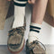 model wearing taupe suede slip on boat shoe with tie top and fringe detail and white crew socks