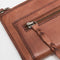 up close of model holding brown leather zip wallet with braided zipper pull