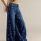 side view of model wearing dark denim barrel jeans with all over embroidered silver fish and shell print