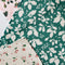 up close of set of three holiday dish cloths: pink with holly print, green with shadow holly print, and white with dainty sprig print