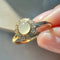 up close of gold band ring with opal stone surrounded by crystal stone border