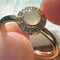 up close of gold band ring with opal stone surrounded by crystal stone border