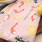 side view of light pink cotton tea towel with shrimp cocktail and lemon print