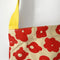 up close of pale yellow wine tote with abstract poppy red floral print