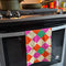 pink, orange, yellow and green diamond tea towel on a oven handle
