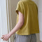 Back view of model wearing mustard yellow tee with ringer neckline and muscle tee sleeves