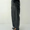 side view of model wearing shiny black relaxed fit pants with side inlets