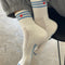 model wearing cream high crew socks with triple light blue stripes and embroidered red heart