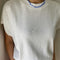 up close of model wearing white relaxed tee with muscle tee sleeves and side vents at the hem