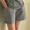 side view of model wearing navy and white gingham cotton shorts with side pockets