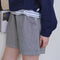 side view of model wearing thin navy and white stripe shorts with side pockets and exposed hem at the bottom