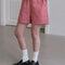 side view of model wearing red and white gingham cotton shorts with side pockets
