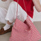 model holding red and white gingham rectangular bag