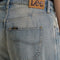 up close of model wearing gritty medium wash loose crop button fly jeans with distressing on the legs