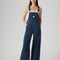 model wearing relaxed fit dark blue overalls with a white tank
