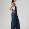 side view of model wearing relaxed fit dark blue overalls with a white tank