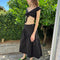 side view of model wearing black twill midi skirt with wavey hem detail