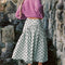 back view of model wearing mint asymmetrical dot midi skirt with purple cardigan